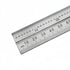 A stainless steel ruler with both inch and millimeter scales, shown diagonally on a plain white background.