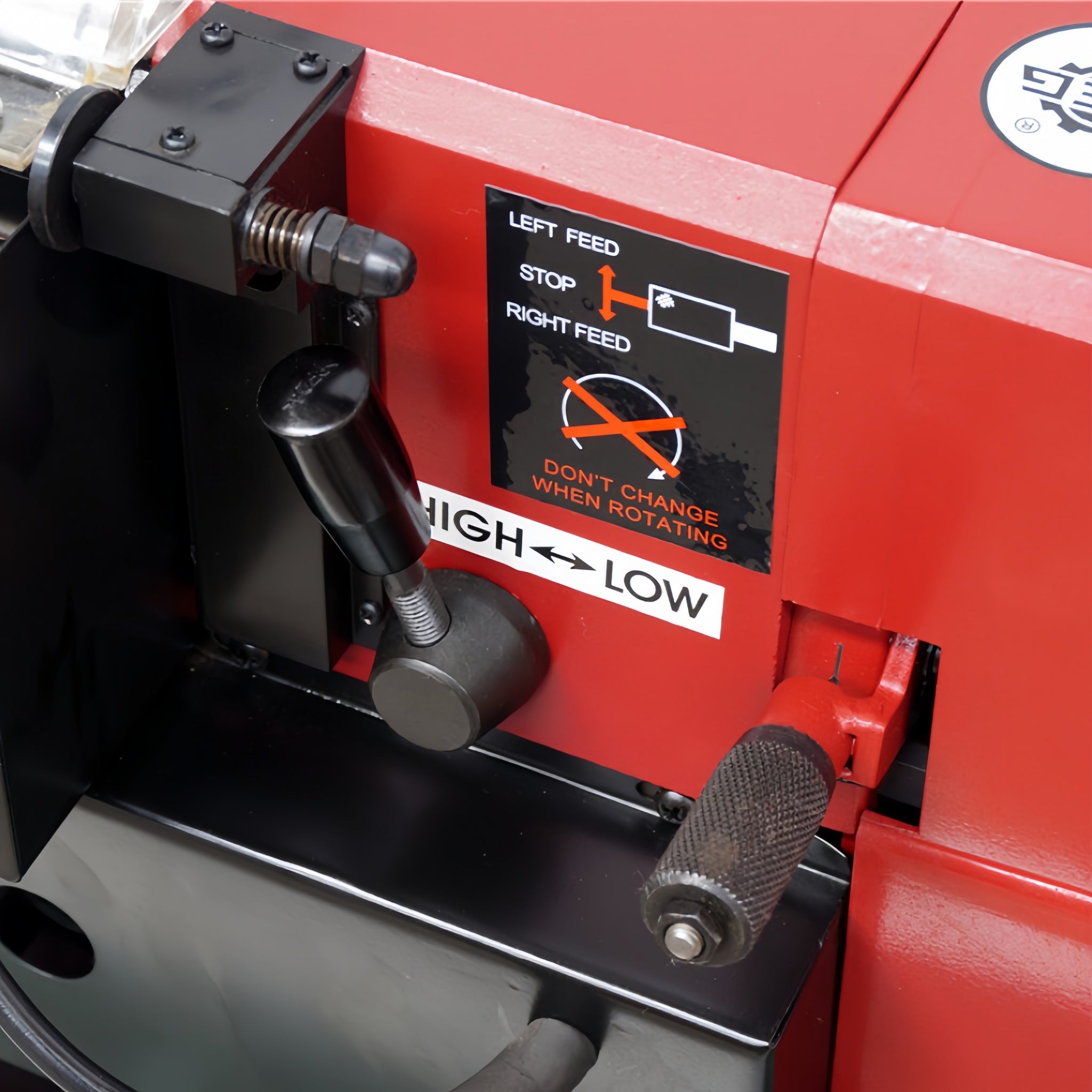 Close-up of a red and black industrial machine control panel with adjustment levers, a black instruction label reading left feed, stop, right feed, and high/low, plus a visible Ausee Machines & Tools watermark at the bottom.