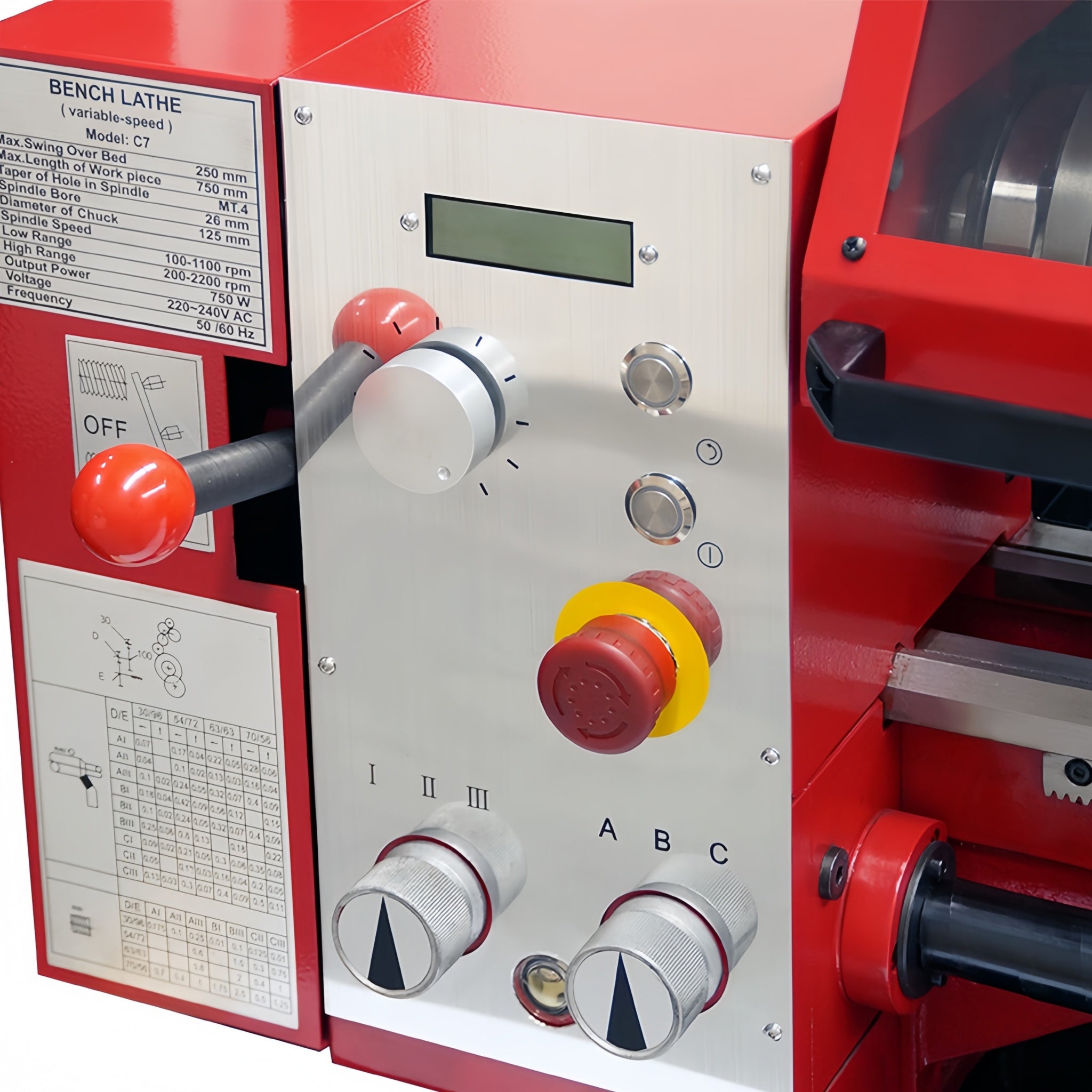 Close-up of a red and silver bench lathe control panel with large red and white knobs, a small digital display, and printed operation labels and diagrams.