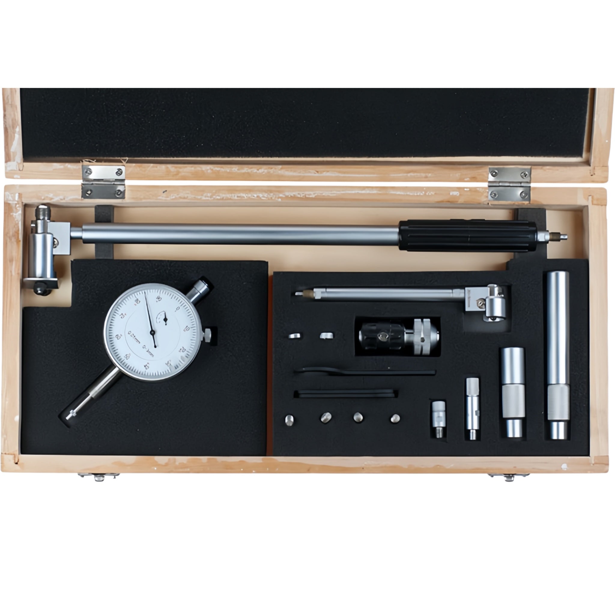 A precision dial indicator and measuring tool kit displayed inside an open wooden presentation box with black foam inserts. The kit includes a dial indicator, a long measuring rod with a black handle, several metal collars and adapters, small wrenches or screwdriver bits, and other small hand tools, all arranged neatly on a white background.
