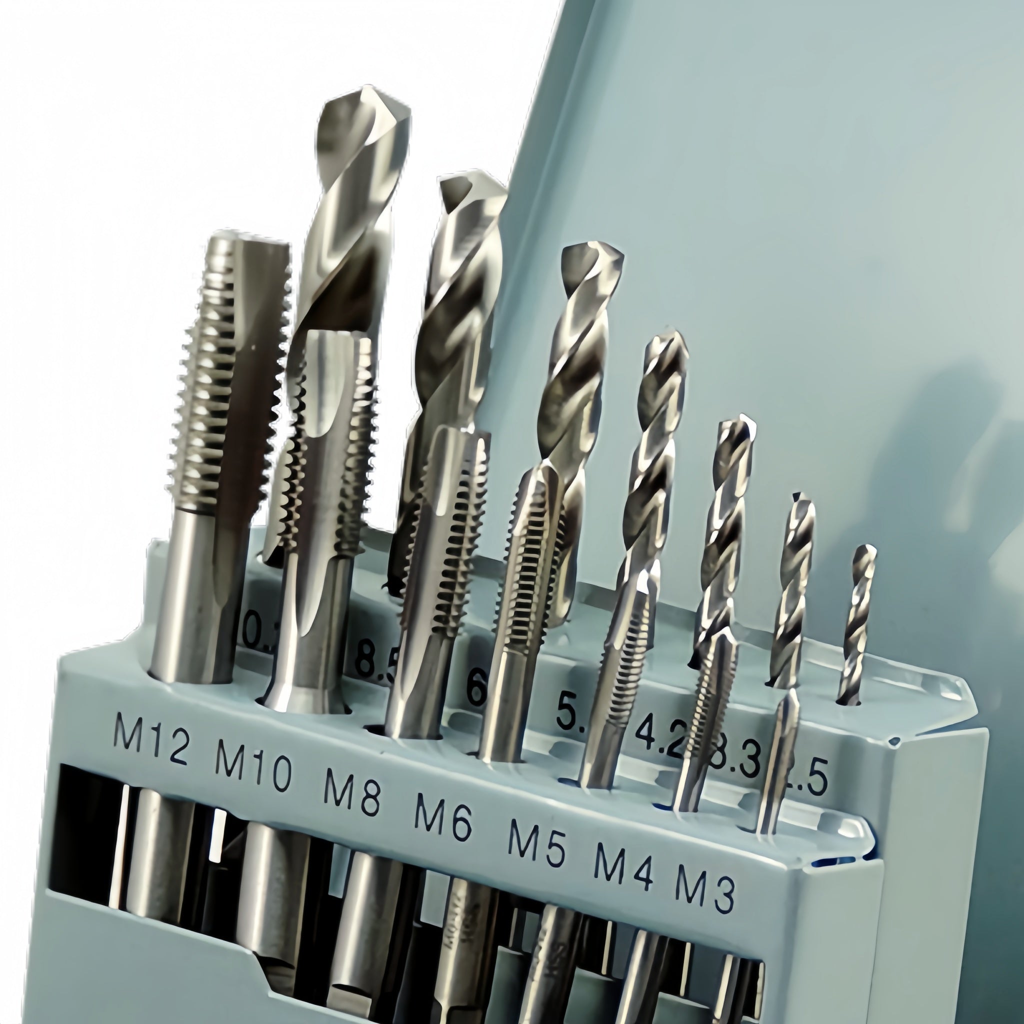 Set of drill bits and hand taps in a holder with size markings on a white background