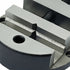 Close-up of a heavy-duty metal clamp or vise with a matte black body and silver-gray machined surfaces, showing threaded components and a circular hole on the front.