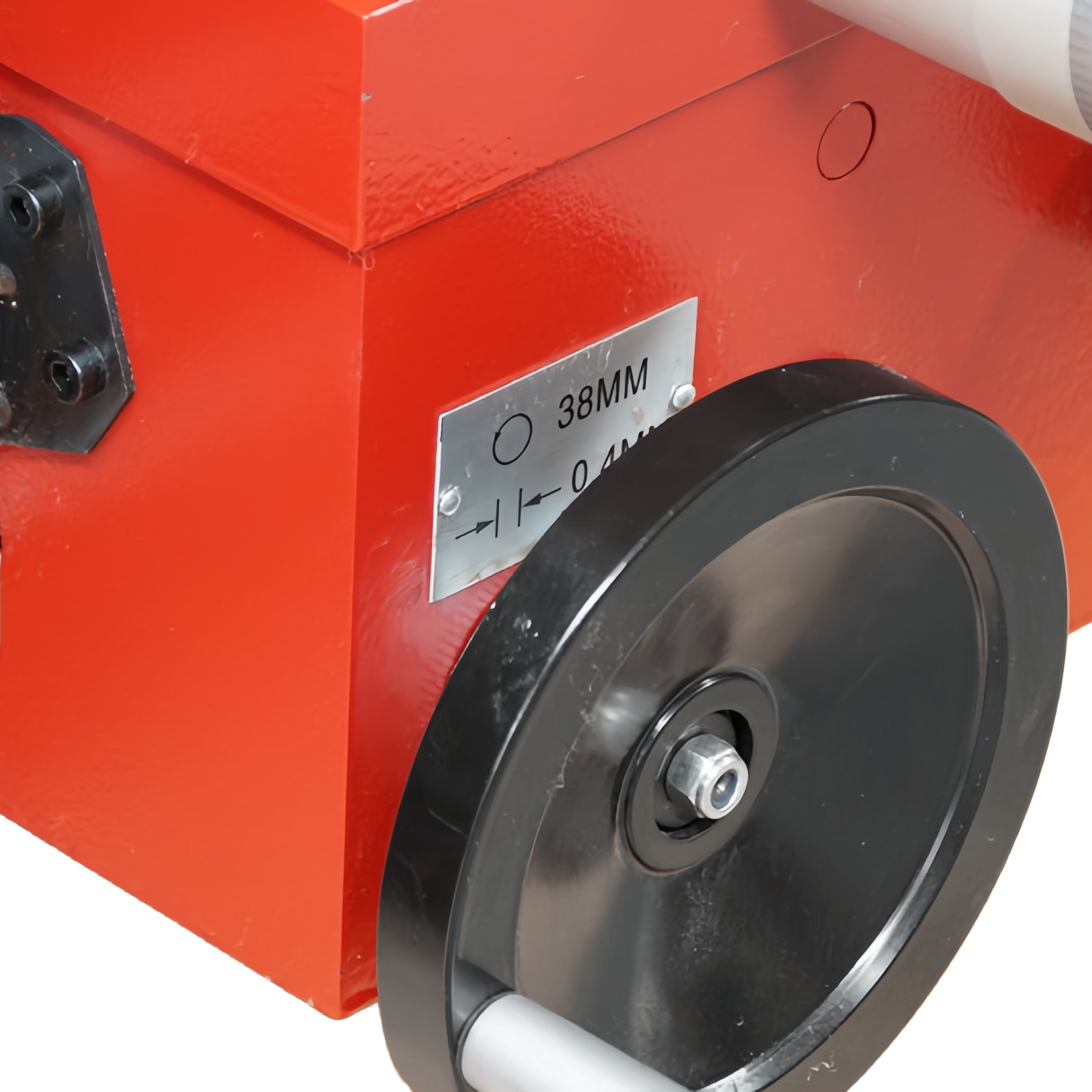 Close-up of a red industrial machine component with a black circular wheel, a black cylindrical tube, and a small metal label reading 38MM.