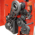 Close-up of a red industrial machine with metal gears, pulleys, belts, and an orange electrical component mounted on the side.