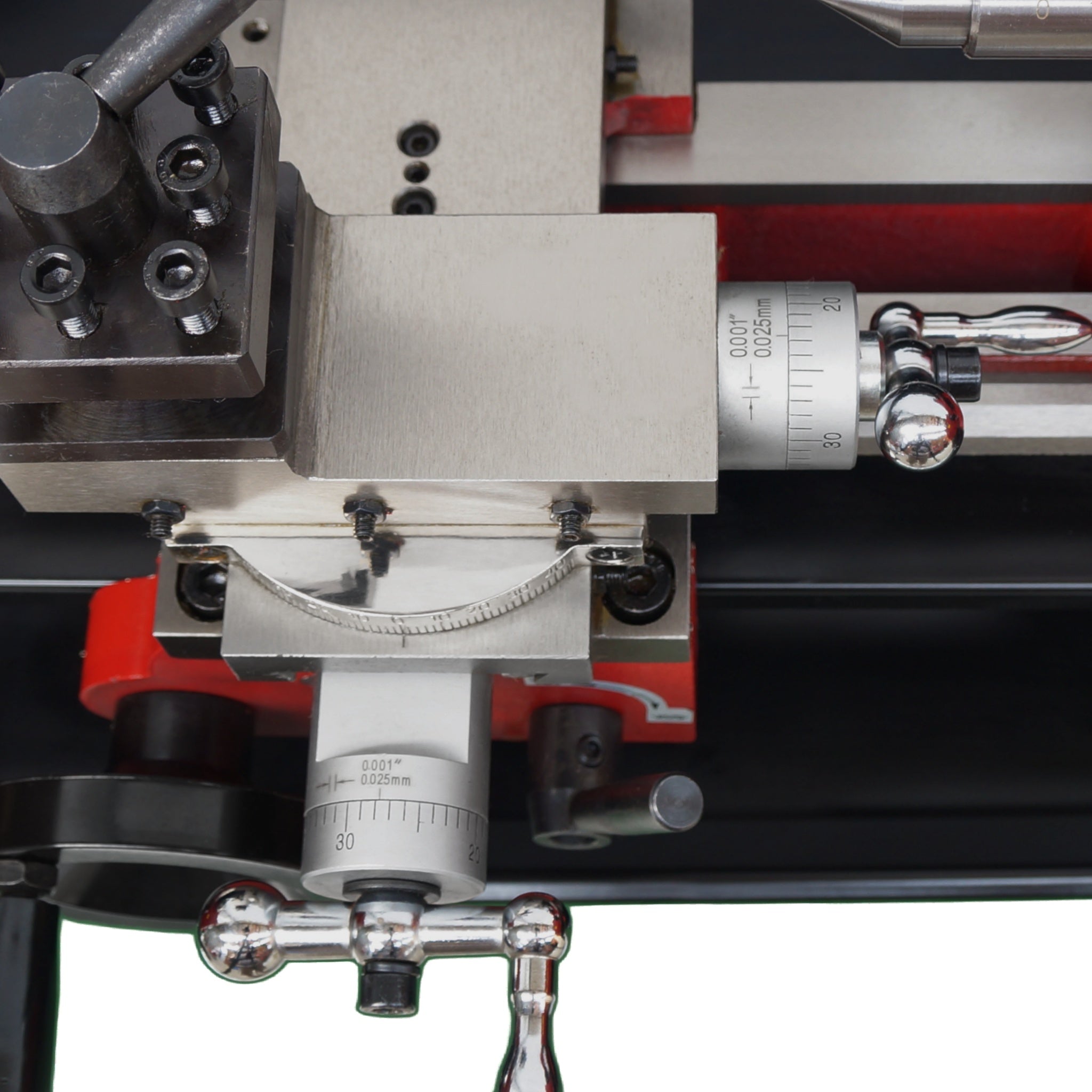 Close-up of a precision mechanical dial with silver metal components, red adjustment blocks, and white measurement scales on a black base.