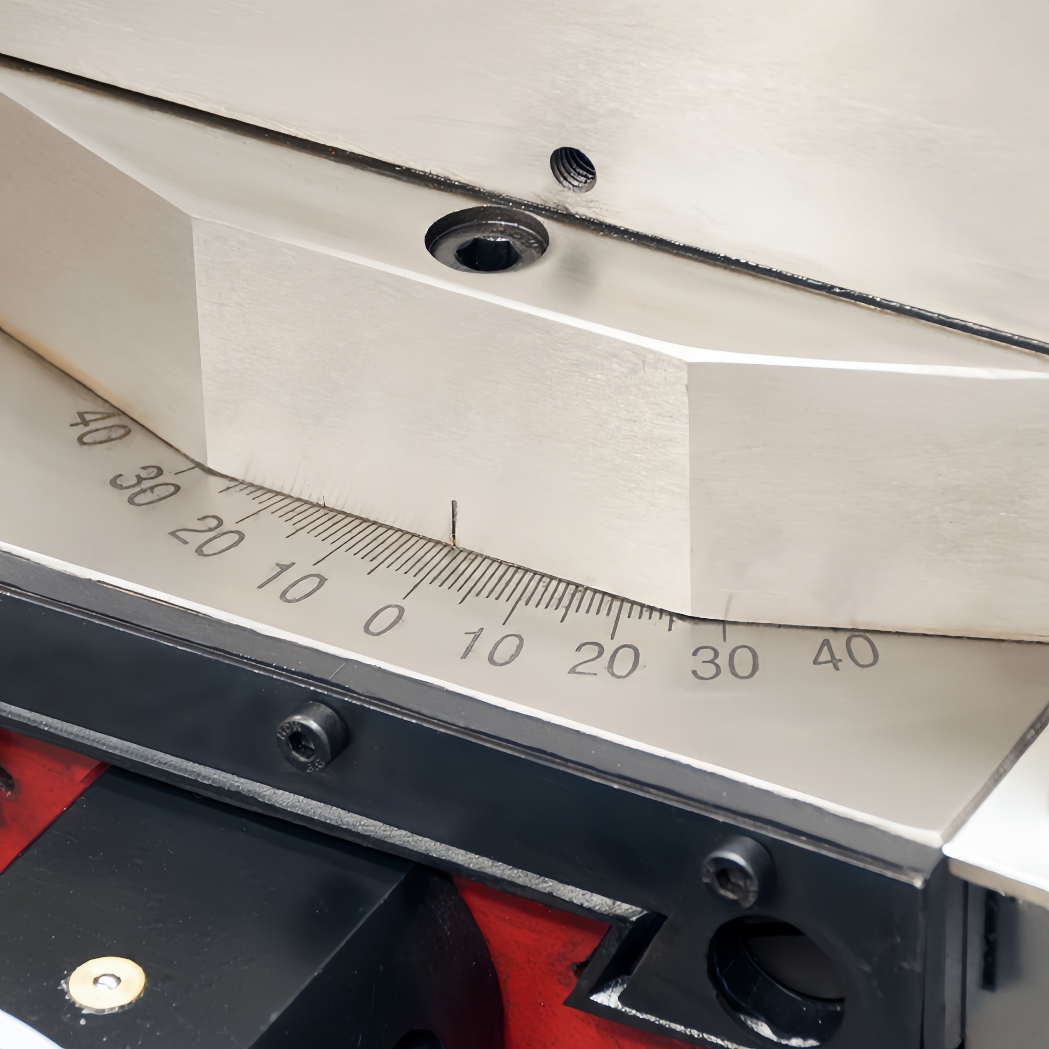A close-up of a metallic three-claw lathe chuck mounted on a red industrial machine body.