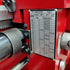 Close-up of a mechanical indicator gauge with a scale on a red machine.