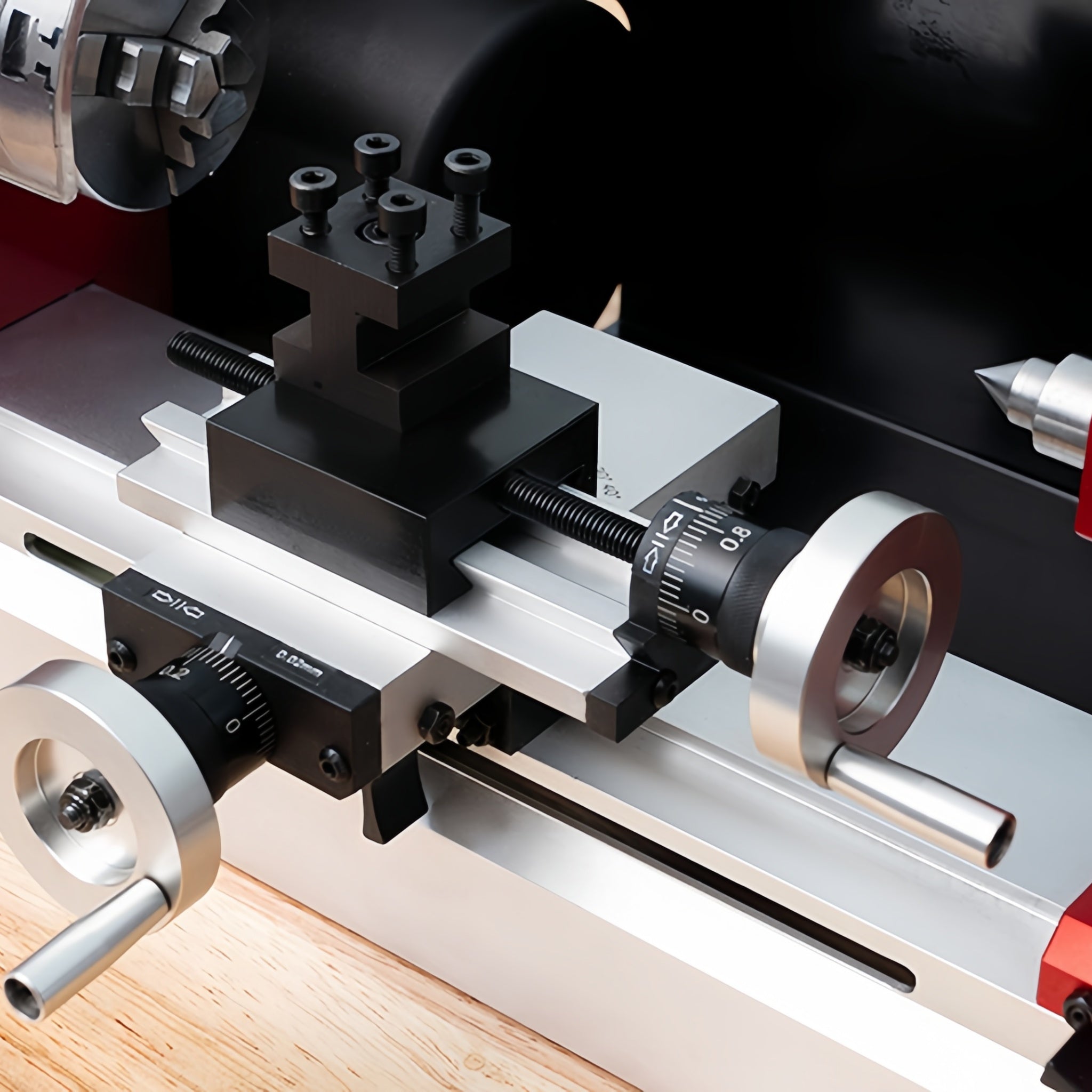 Close-up of a metal lathe tailstock and carriage assembly with black and silver components, shown in detail on a machine bed.
