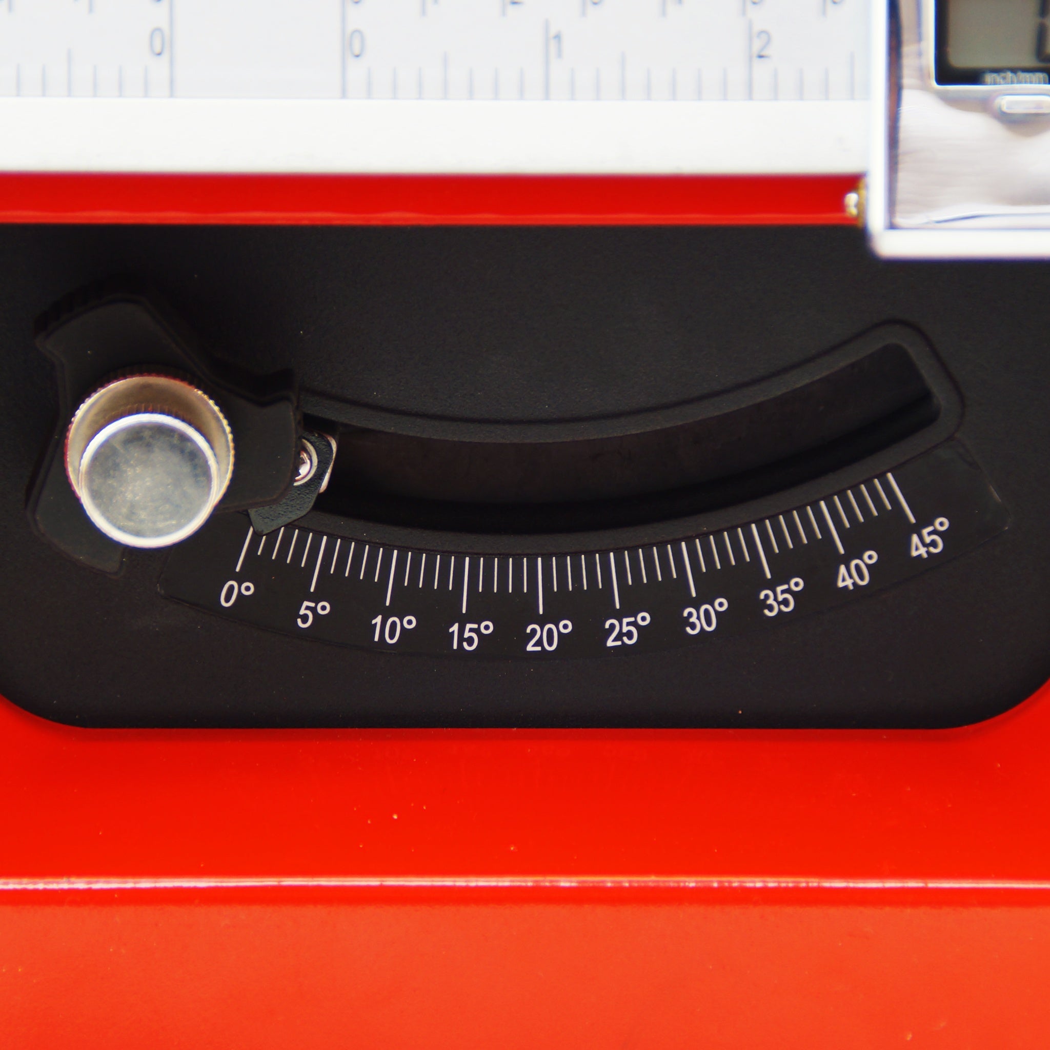 Close-up of a black dials and gauges on a red machine, showing a temperature or angle scale from 0 to 45 degrees.