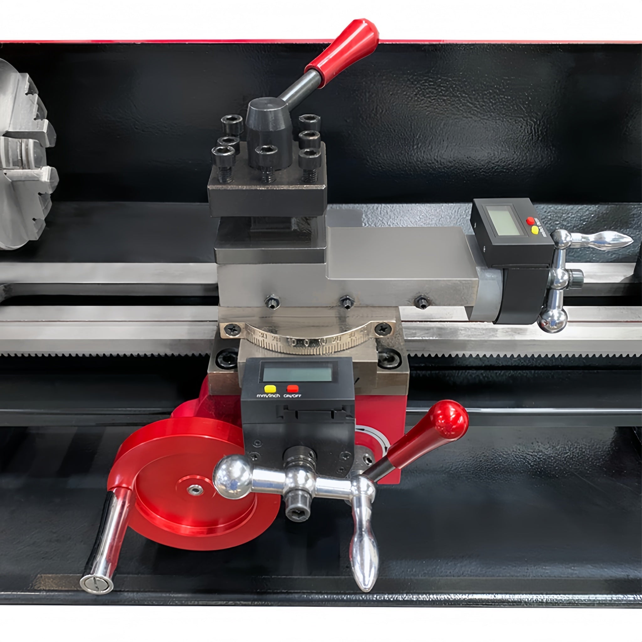 A close-up of a metal lathe machine headstock and carriage assembly with red adjustment handles, silver metal rods, and small digital control screens on a black machine bed.